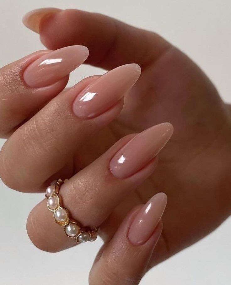 Glossy pearly nude pink almond nails with vintage pearl ring