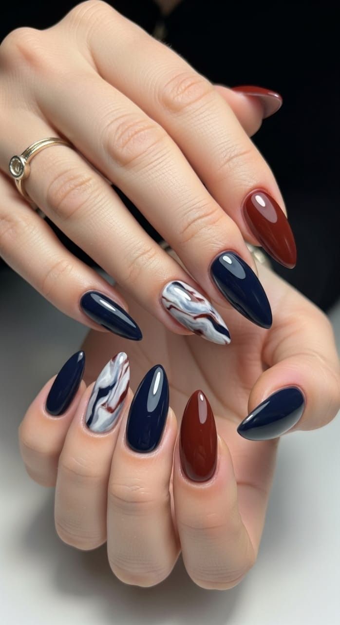Navy and maroon stiletto nails with a single hand-painted marble accent