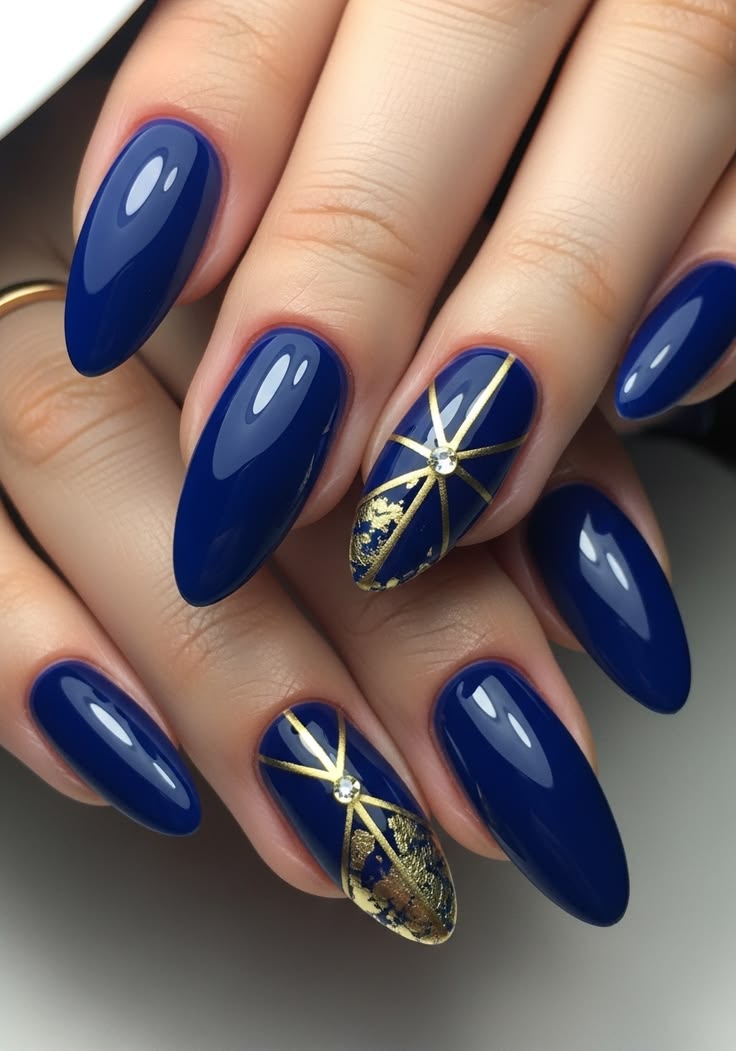 Royal blue nails with hand-painted gold geometric lines and rhinestone accents
