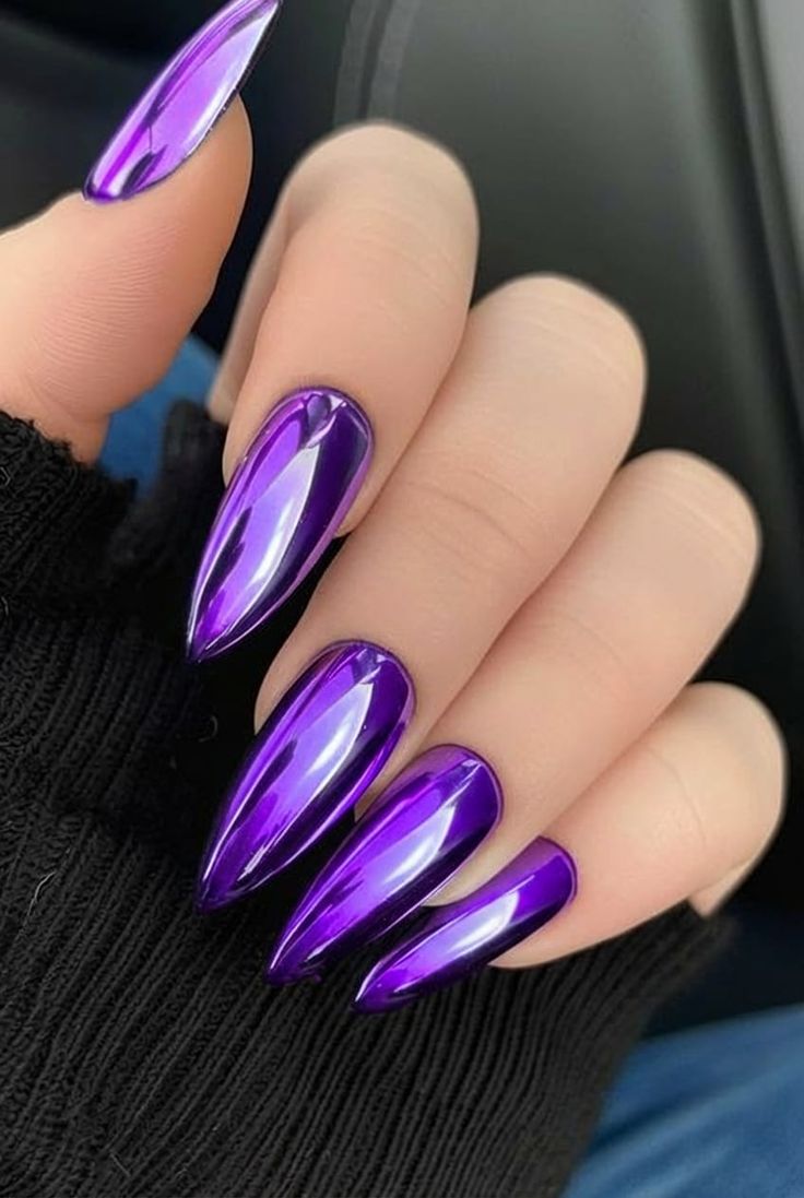 Mirror violet purple chrome stiletto nails against a black knit sleeve